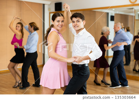 Young pair practicing ballroom dance in dance studio Young pair practicing ballroom dance in dance studio 135303664