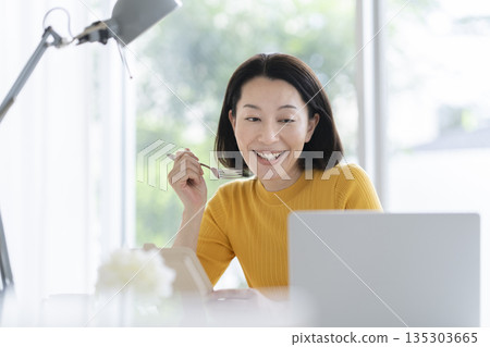 一張五十多歲女性在辦公桌前吃午餐的照片 一張五十多歲女性在辦公桌前吃午餐的照片 135303665