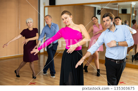 Cheerful man and woman practicing ballroom dances in ballroom 135303675