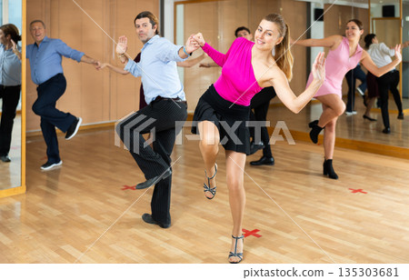 Woman and man enjoying rock and roll dance in studio Woman and man enjoying rock and roll dance in studio 135303681