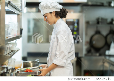 Girl cook in kitchen finely slices food Girl cook in kitchen finely slices food 135303710