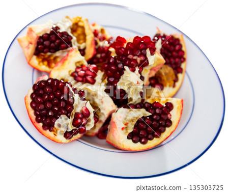 Pieces of ripe pomegranate on a plate top view 135303725