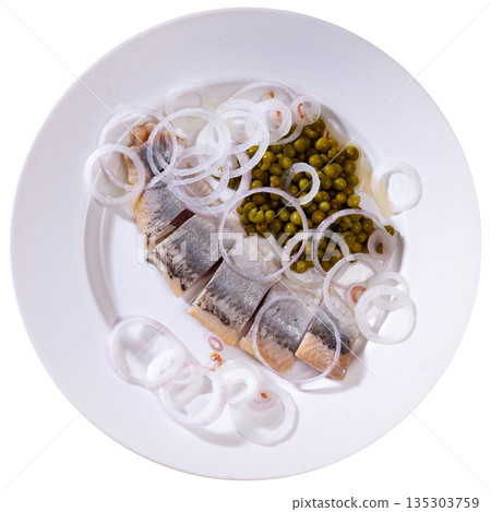 Herring with chopped onion and green peas on a round plate 135303759