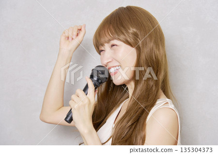 中年婦女手持麥克風唱歌，肖像，灰色背景 135304373