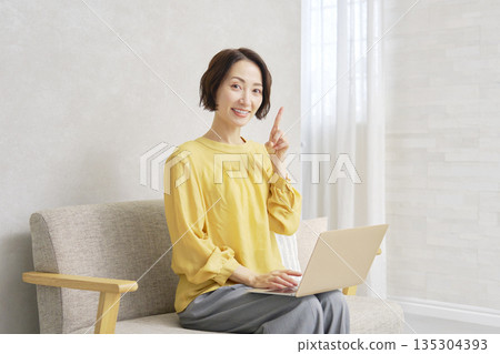 一位女士在客廳使用電腦，並指向… 135304393
