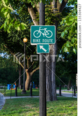 A green sign with a bike route arrow pointing to the right 135304427