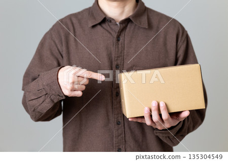 Middle-aged man pointing at cardboard box luggage Middle-aged man pointing at cardboard box luggage 135304549