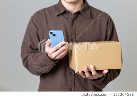 Middle-aged man holding cardboard box luggage and smartphone Middle-aged man holding cardboard box luggage and smartphone 135304551