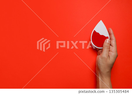 Hand shows a paper drop on a red background 135305484