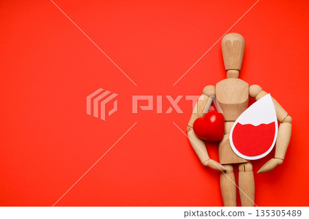 Wood figure with heart and blood drop on red background Wood figure with heart and blood drop on red background 135305489