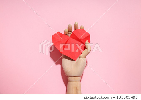 Wooden craft with a red origami heart on pink 135305495