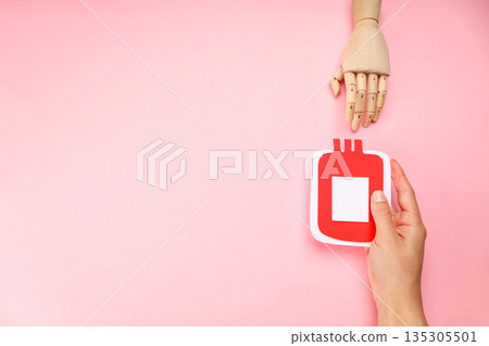 Hand with red blood donation bag on pink background Hand with red blood donation bag on pink background 135305501