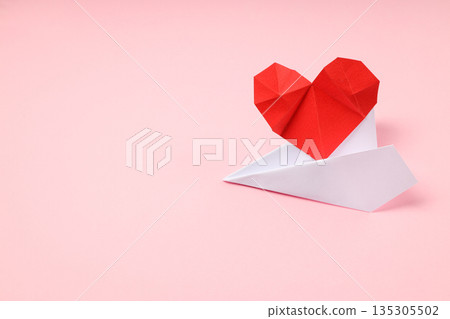 Origami heart on a paper airplane, pink backdrop Origami heart on a paper airplane, pink backdrop 135305502