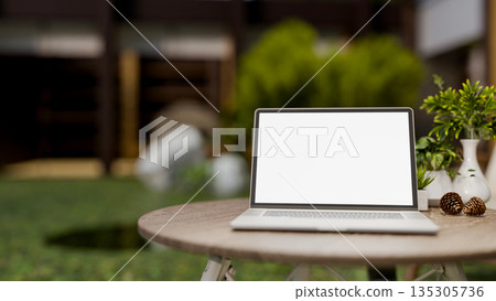 White screen laptop with decor acorn and flower vase on round wooden table in a garden or backyard. White screen laptop with decor acorn and flower vase on round wooden table in a garden or backyard. 135305736