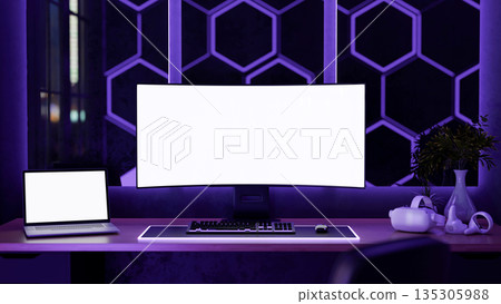 Blank screen computer and laptop with headset on wooden table with neon purple monitor backlighting. 135305988