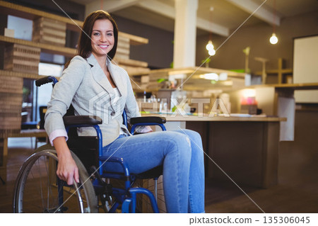 Woman smiling while sitting in wheelchair in office kitchen near coffee maker and plants Woman smiling while sitting in wheelchair in office kitchen near coffee maker and plants 135306045