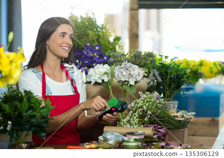Female florist trimming hydrangea stem with green-handled cutter at flower shop bench, copy space Female florist trimming hydrangea stem with green-handled cutter at flower shop bench, copy space 135306129