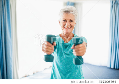 Senior woman lifting teal dumbbells and wearing teal exercise shirt in home exercise area Senior woman lifting teal dumbbells and wearing teal exercise shirt in home exercise area 135306164