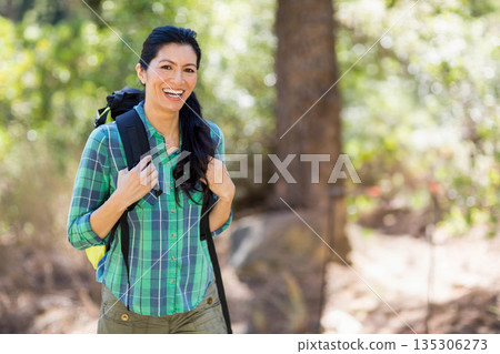 Asian woman standing on wooded trail wearing green shirt with black and yellow backpack, copy space Asian woman standing on wooded trail wearing green shirt with black and yellow backpack, copy space 135306273