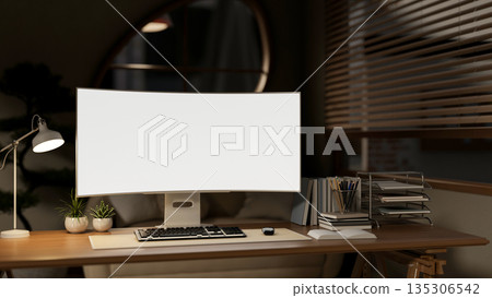 Blank screen computer and document folders aside lamp on wooden working table in dim lit living room 135306542