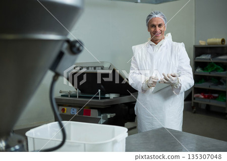 Male technician holding tablet while inspecting hopper in food production plant, copy space Male technician holding tablet while inspecting hopper in food production plant, copy space 135307048