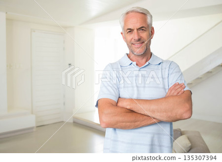 Mature man standing with arms crossed by white paneled door in minimalistic living room, copy space 135307394