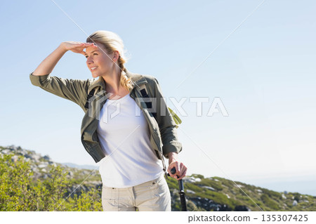 Woman shading eyes scanning horizon on rocky hillside with trekking pole and backpack, copy space Woman shading eyes scanning horizon on rocky hillside with trekking pole and backpack, copy space 135307425