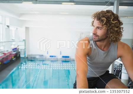 male athlete in activewear sitting on bench by pool, blue lane floats, starting blocks, copy space male athlete in activewear sitting on bench by pool, blue lane floats, starting blocks, copy space 135307552