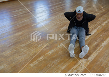 African American man wearing backward cap performing tricep dip in fitness studio, copy space 135308286