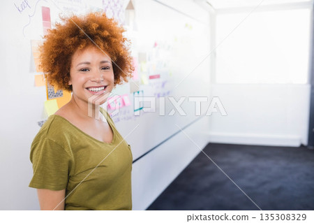 African American woman standing by whiteboard with sticky notes and diagrams in office, copy space 135308329