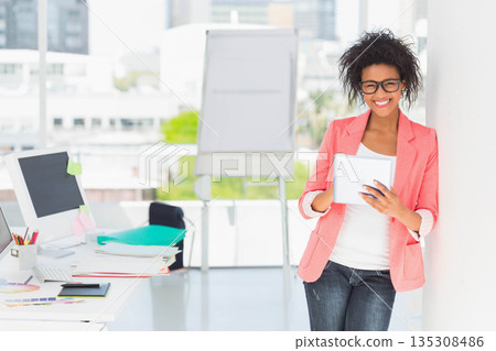 African American woman in coral blazer leaning, holding tablet at office swatch palette copy space 135308486