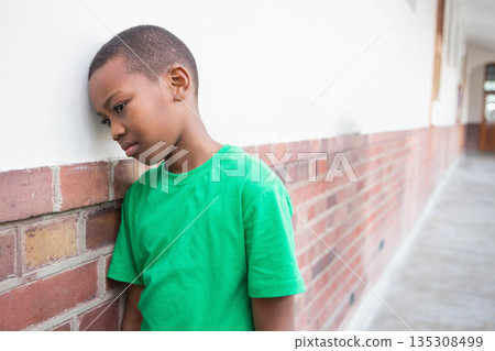 African American child boy leaning head against low brick half-wall in corridor, copy space African American child boy leaning head against low brick half-wall in corridor, copy space 135308499