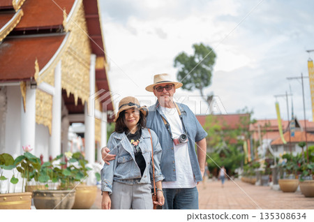 Old white man holding hugging asian woman wife standing together in front of ancient buddhist temple 135308634