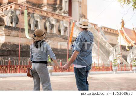 Man and woman couple in denim holding hand standing and looking at ancient pagoda in buddhist temple 135308653
