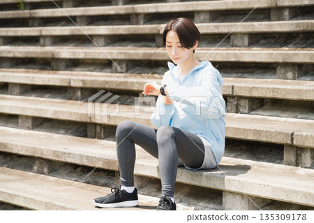 年輕女子正在查看她的運動手錶。運動圖片。 135309178