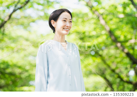 A young woman looking up at the tree-lined street Lifestyle image A young woman looking up at the tree-lined street Lifestyle image 135309223