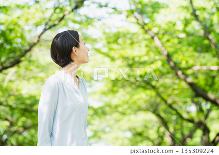 A young woman looking up at the tree-lined street Lifestyle image A young woman looking up at the tree-lined street Lifestyle image 135309224