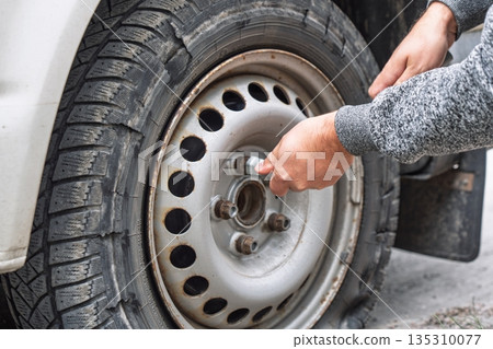 Replacing a Flat Tire Mechanic Changing Car Tire on Roadside for Safety and Maintenance 135310077