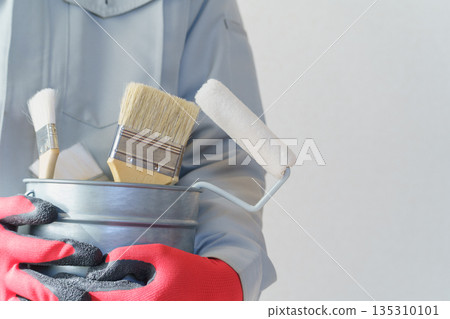 身穿工作服的人手提裝滿刷子和滾筒的水桶 | 裝潢、油漆承包商、DIY 圖片 身穿工作服的人手提裝滿刷子和滾筒的水桶 | 裝潢、油漆承包商、DIY 圖片 135310101