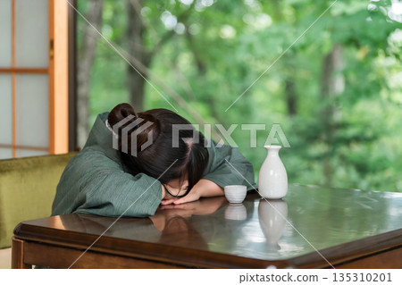 A woman in a yukata falls asleep at the table after drinking too much at a ryokan inn 135310201