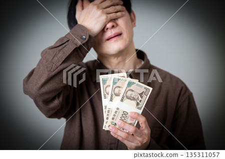 A middle-aged male businessman in casual clothes worried about a wad of cash A middle-aged male businessman in casual clothes worried about a wad of cash 135311057