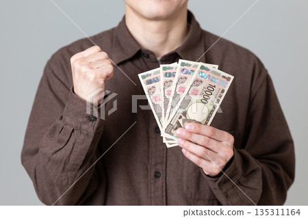 一位身著休閒裝的中年男商人拿著錢大笑。 135311164