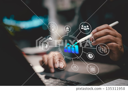 Business analyst using digital pen with virtual graph and data analytics interface over laptop 135311958