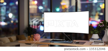 Blank screen computer with calculator, gold coins and piggy bank on table in a room with city lights Blank screen computer with calculator, gold coins and piggy bank on table in a room with city lights 135312046