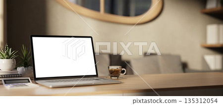 White screen laptop with calculator and coffee aside pot plants on wooden table in a bedroom or living room. 135312054