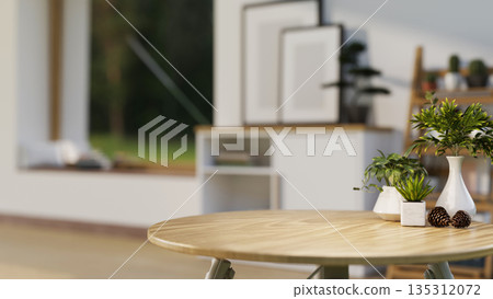 Potted plants and flower vase with decors acorns on a round wooden table in a cosy living room or bedroom. Potted plants and flower vase with decors acorns on a round wooden table in a cosy living room or bedroom. 135312072