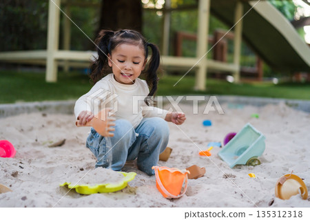 happy child girl playing sand with toy on playground 135312318