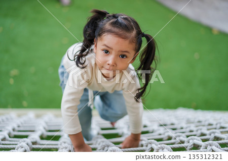 happy child girl playing with climbing ropes net at outdoor playground happy child girl playing with climbing ropes net at outdoor playground 135312321