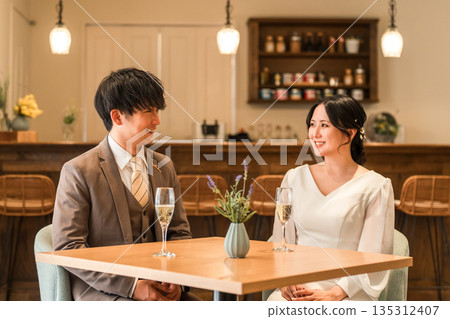 A couple in a dress code having a conversation while drinking champagne at a restaurant or bar A couple in a dress code having a conversation while drinking champagne at a restaurant or bar 135312407