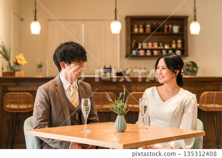 A couple in a dress code having a conversation while drinking champagne at a restaurant or bar A couple in a dress code having a conversation while drinking champagne at a restaurant or bar 135312408